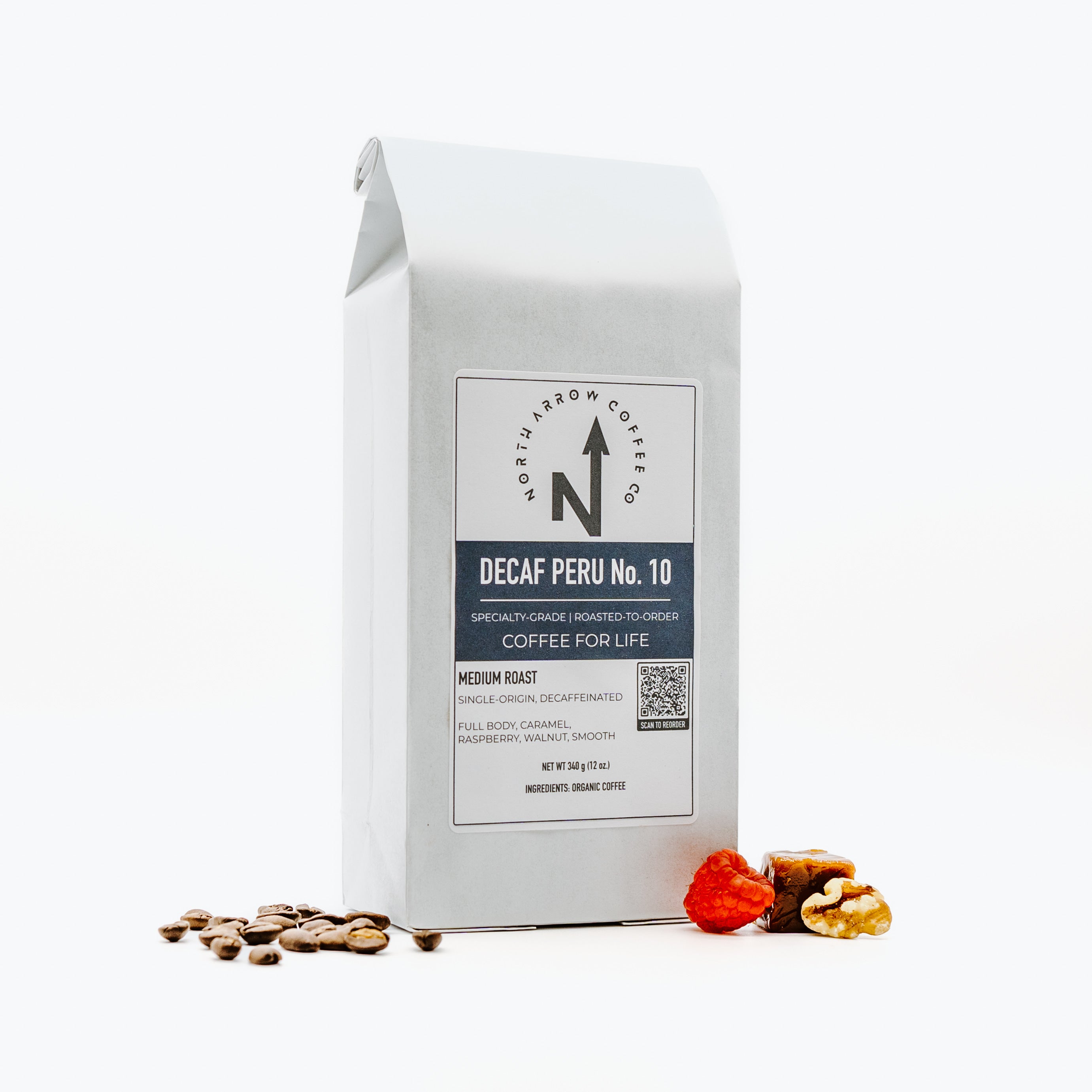 A packaged bag of Decaf Peru No. 10 coffee beans with a white label, some coffee beans are scattered in front of the package.