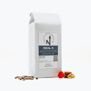 A packaged bag of North Arrow Coffee Company's Peru No. 10 coffee with coffee beans displayed in front.